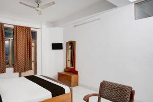 菩提伽耶Hotel O Buddha Statue Gaya Formerly Uruvela International的一间卧室，里面有一张床、一把椅子和几扇窗户。