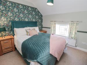 a bedroom with a bed with a green comforter and a window at Inglenook Cottage in Guisborough