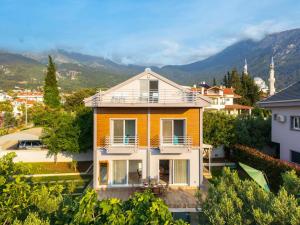 een geel huis met een balkon en bergen op de achtergrond bij Villa Mira in Ovacik
