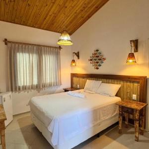 a bedroom with a large white bed and two lights at Pousada Caponga Praia Mar in Cascavel