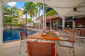 a restaurant with tables and chairs next to a pool at Stylish 2BR Resort Condo with Seaview Surin in Phuket