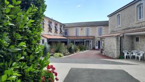 a courtyard of a building with chairs and plants at CIT'HOTEL Le Commerce in Saujon