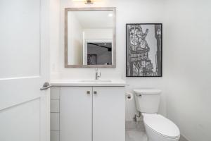a white bathroom with a toilet and a mirror at The Saddlery-Playlist-2 Units-Walk to Broadway in Nashville +71 photos