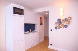 a kitchen with white cabinets and a tv on the wall at PANORAMA view premium class rooms in Batumi