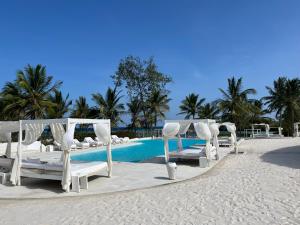 a group of beds on the beach near a pool at Watamu Shell House in Watamu