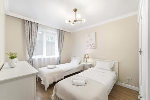 a white room with two beds and a window at Charming French Getaway Spacious Apartment with Garden and Parking in Dumbrăviţa