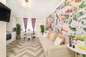a living room with a couch and a floral wall at Charming French Getaway Spacious Apartment with Garden and Parking in Dumbrăviţa