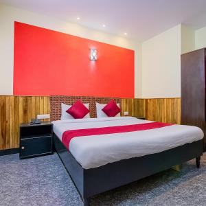 a bedroom with a large bed with a red wall at LIMRA INN RESIDENCY cottage in Ooty