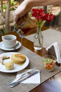 a table with a plate of food and a vase with red flowers at Intercity Cuiabá in Cuiabá
