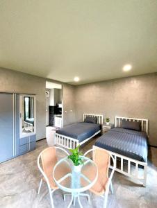 two beds in a room with a table and chairs at Dee Dee Apartments ChumPhae in Chum Phae