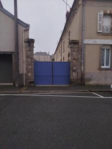 an empty street with a blue gate between two buildings at Appartement cocooning in Laval