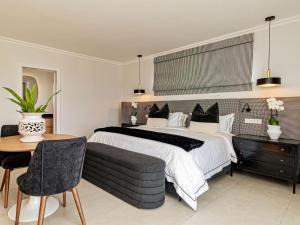 a bedroom with a large bed and a table and chairs at Plettenvale Wines in Plettenberg Bay