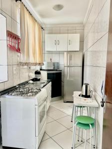 a kitchen with white appliances and a green stool at Apartamento completo no centro da cidade in Passo Fundo