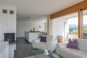 un soggiorno con mobili bianchi e una grande finestra di Edelweiss Casa Cassons a Flims