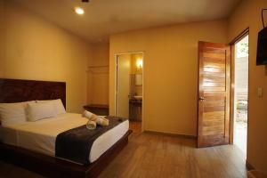 um quarto com uma cama e uma porta para um banheiro em Hotel Boutique Bahia Azul em Bacalar