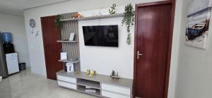 a living room with a television on a wall at Apartamento Princesinha do Mar in Guriri