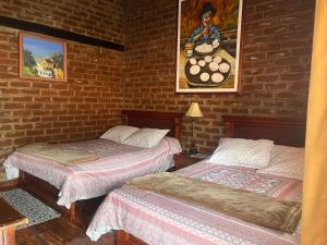 una camera con due letti e un muro di mattoni di La Rustica Hotel a Guaranda