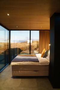 a bedroom with a bed with a large glass window at Mirror Suite in Hjarðarholt