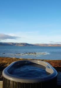 a hot tub in front of a body of water at Mirror Suite in Hjarðarholt +14 photos