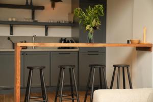 Eine Küche mit Barhockern und einer Theke mit einer Blumenvase. in der Unterkunft Cevizdibi Loft Villa in Kartepe