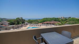 マーゲートにあるFalling Waters Guest Houseのバルコニー(テーブル、椅子付)、スイミングプールが備わります。