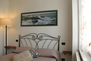 Lunigiana - Casa Anita Con Giardino في كاستيلنوفو ماغرا: غرفة نوم بها سرير وصورة على الحائط