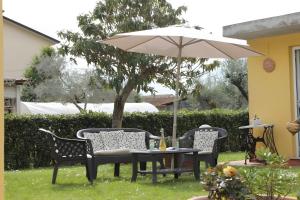 Lunigiana - Casa Anita Con Giardino في كاستيلنوفو ماغرا: طاولة وكراسي ومظلة في الفناء