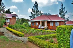 une maison en bois avec un toit rouge et un jardin dans l'établissement Bwigamiro Country Home Fort Portal, à Fort Portal