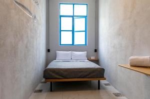 墨西哥城Hostal CASA MX bellas artes的一间小卧室,配有一张带蓝色窗户的床