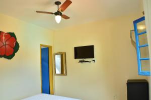 a bedroom with a ceiling fan and a television on the wall at Pousada Recanto das Araras in Tiradentes