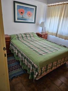 una camera da letto con un letto con una coperta verde di Departamento Villa Gesell 3 cuadras de la playa a Villa Gesell