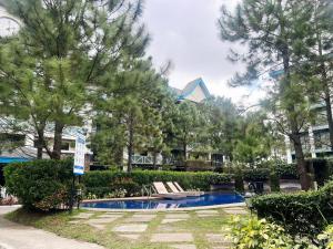 a swimming pool in a park with trees and a building at Belle Maison in Pine Suites Tagaytay in Tagaytay