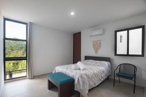 una camera da letto con un letto, una sedia e una finestra di Casa Cholul a Cholul