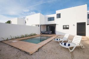 una casa bianca con piscina e due sedie di Casa Cholul a Cholul