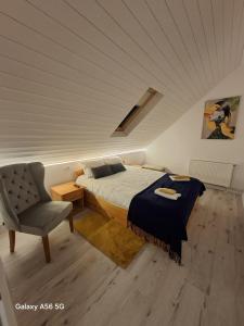 ein Schlafzimmer mit einem Bett und einem Stuhl auf einem Dachboden in der Unterkunft Max River Chalet in Porumbacu de Sus