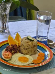 a plate of food with eggs and vegetables and a glass of water at Fil-Can Hostel Coron in Coron