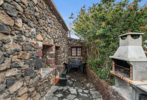a stone wall with a bench next to a building at Casa Rural Higuera Morales in Mocanal