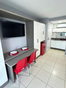 ジョアンペソアにあるMelhores Flats - Maravilhosa varanda frente ao marのキッチン(テーブル、赤い椅子2脚付)