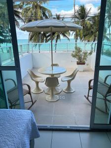 ジョアンペソアにあるMelhores Flats - Maravilhosa varanda frente ao marのテーブルと椅子と傘のあるパティオ