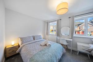 a bedroom with a bed and two windows at Modern Hastings Home for Groups with Garden Terrace and Dedicated Workspace in Hastings