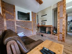 Skazdub StarySummer house in Suwalszczyzna- Dom w Dolinie Rospudy的带皮沙发和壁炉的客厅