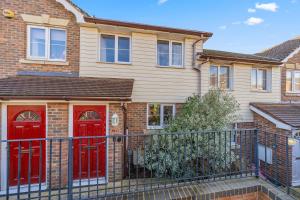 a house with red doors and a black fence at Modern Hastings Home for Groups with Garden Terrace and Dedicated Workspace in Hastings