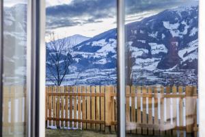 Una ventana con vista a una montaña cubierta de nieve. en Vronis Lodge, en Hart im Zillertal