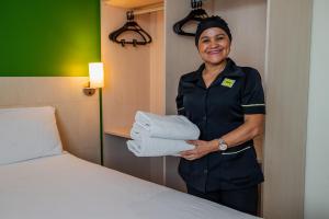 a woman in a hotel room holding a pile of towels at ibis Styles Belem Batista Campos in Belém