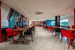 a dining room with tables and red chairs at ibis Styles Belem Batista Campos in Belém