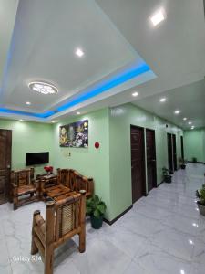 a lobby with green walls and wooden furniture and a television at Fil-Can Hostel Coron in Coron