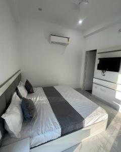 a white bedroom with a large bed and a television at Sky s whiye house in Ludhiana