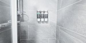 a bathroom with a shower with three bottles of soap at The Burford Hideaway in Nottingham
