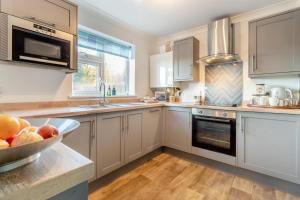 una cucina con armadi bianchi e un cesto di frutta sul bancone di 1 Pump Cottages a Theberton Altre 16 foto