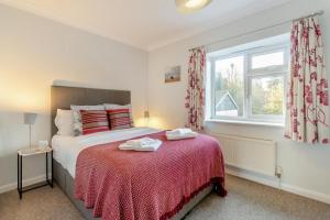 una camera da letto con un letto con una coperta rossa e una finestra di 1 Pump Cottages a Theberton